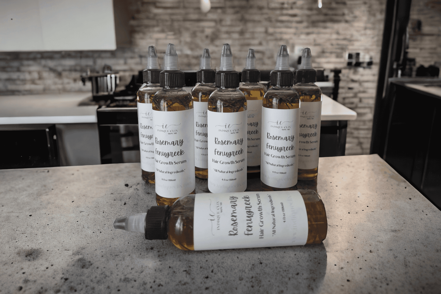 Multiple bottles of labeled Rosemary and Fenugreek Infused hair growth oil on a kitchen countertop