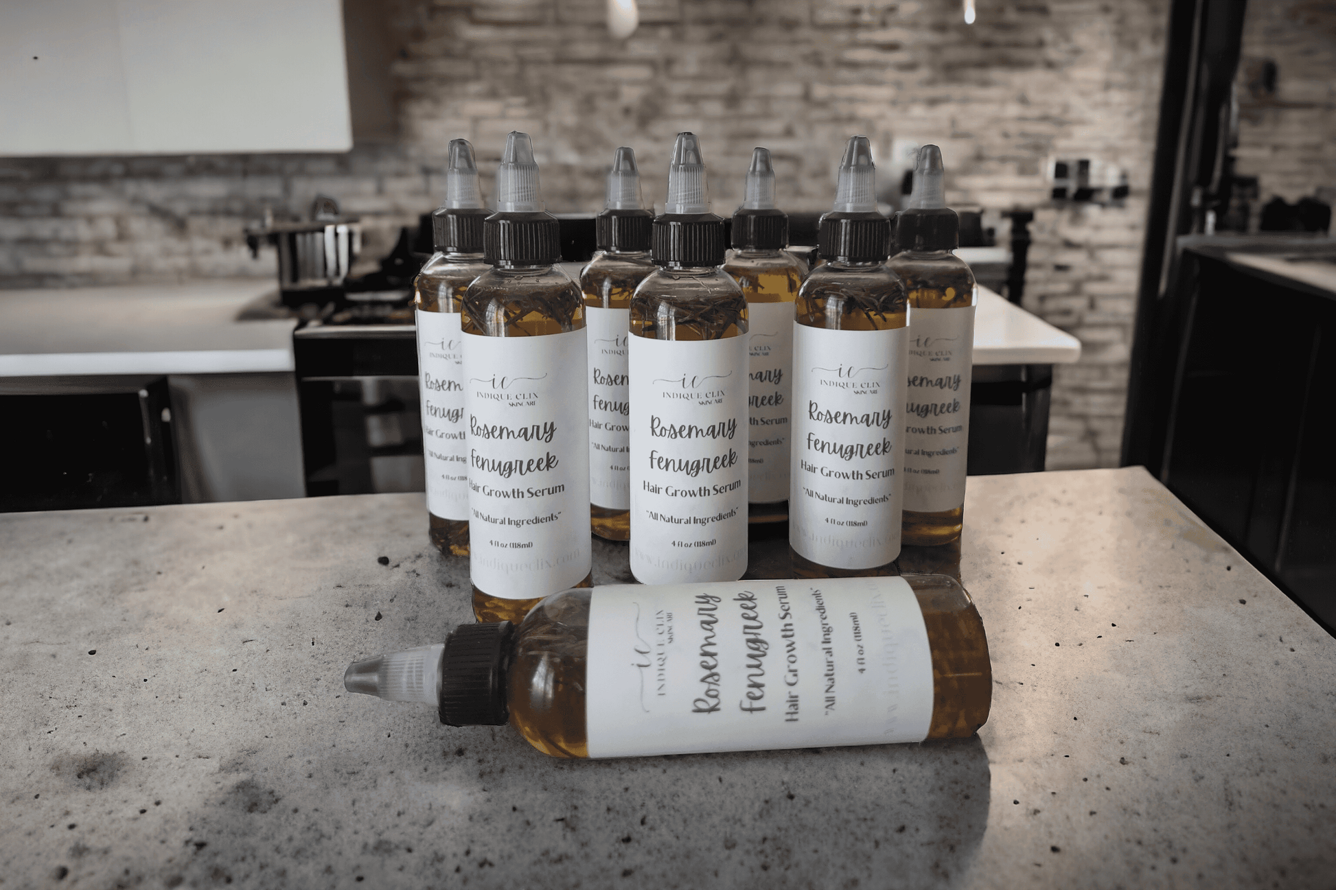 Multiple bottles of labeled Rosemary and Fenugreek Infused hair growth oil on a kitchen countertop 